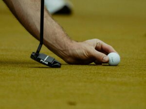 a man lining up a golf ball to putt
